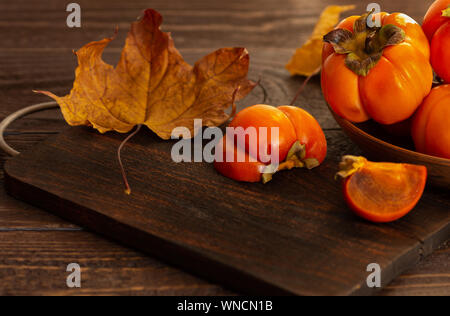 Persimmons maturi su uno sfondo di legno. Persimmon varietà Fuyu. Close-up. Foto Stock