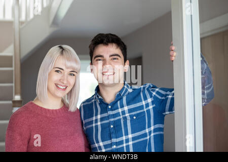 Ritratto di sorridente coppia giovane di apertura della porta anteriore della nuova casa Foto Stock