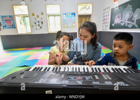 (190906) -- CHONGQING, Sett. 6, 2019 (Xinhua) -- insegnante di volontariato Mu Yi (C) dà una lezione di musica per gli studenti di Lianhua scuola primaria di Luzi Village, Chengkou County, a sud-ovest della Cina di Municipalità di Chongqing, Sett. 3, 2019. Mu Yi, un 25-anno-vecchio insegnante PE dalla Municipalità di Chongqing, offre una settimana di volontariato servizio di insegnamento e le opere di un maestro locale Tao Yao in questo remoto villaggio. Nella scuola dove solo due di secondo grado studenti e 18 bambini di età prescolare studio, Mu Yi e Tao Yao anche fare altri lavori come mandanti, detergenti, i cuochi e repairwomen. Mu Yi insegna ai bambini sport, arte Foto Stock
