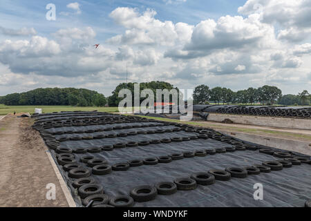 Terreni agricoli olandese con insilati di erba coperta con un foglio di alluminio e pneumatici Foto Stock