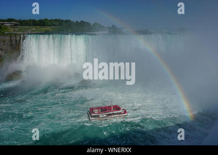 Niagara Falls, Ontario, Canada: un arcobaleno appare sopra il fiume Niagara come un tour in barca porta i visitatori fino ai piedi delle cascate Horseshoe. Foto Stock