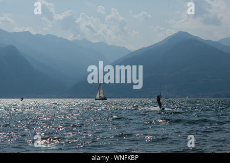 Il lago di Como, Italia - 21 luglio 2019. Sport d'acqua: kitesurfer surf il vento sulle onde e barca su una soleggiata giornata estiva vicino a Colico, città d'Italia. Alp Foto Stock