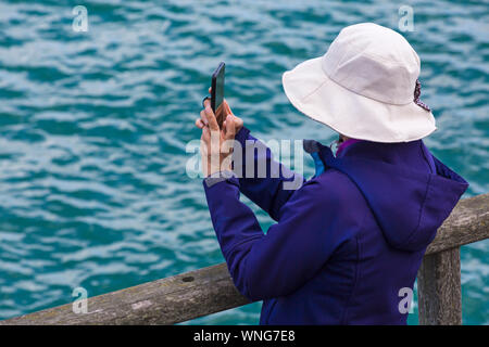 Donna che indossa cappello prendendo foto sul telefono cellulare a Bournemouth Air Festival, Dorset Regno Unito nel mese di agosto Foto Stock