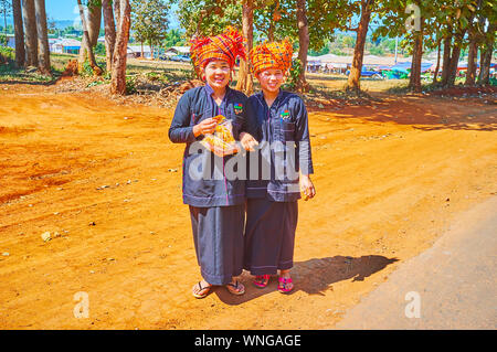 KAKKU, MYANMAR - 20 febbraio 2018: Il Ritratto di giovane donna sorridente di Pa-Oh gruppo etnico in testa tradizionali sciarpe con pacchetti di spuntini locali, Foto Stock