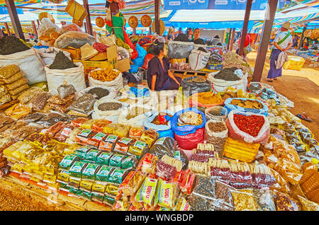 KAKKU, MYANMAR - Febbraio 20, 2018: La Spezia stallo del mercato agricolo con i pacchetti e i sacchetti di spezie, tè, noci, legumi secchi e snac locale Foto Stock