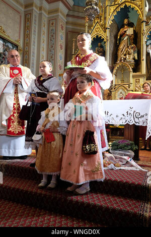 La gente vestita in regionali tradizionali costumi folk in chiesa durante la Santa Messa il giorno del Ringraziamento in Stitar, Croazia Foto Stock