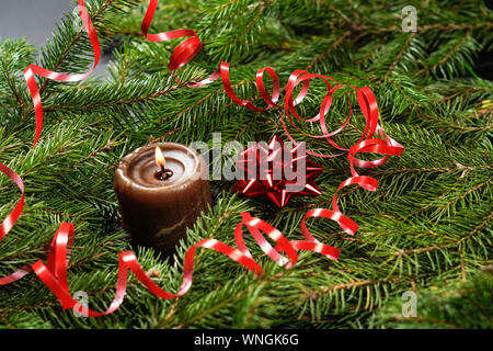 Sfondo di legno con i rami di un albero di Natale e una candela rossa. Foto Stock