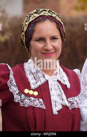 Donna vestito in costumi folcloristici andare in chiesa durante la Santa Messa il giorno del Ringraziamento in Stitar, Croazia Foto Stock