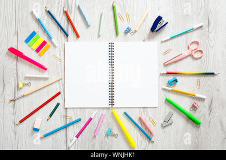 Si torna a scuola Concetto, layout creativi con con varie forniture scolastiche e carta bianca notepad con copia spazio su sfondo di legno. Appartamento in stile laici Foto Stock