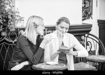 Letteratura femminile. La lettura del libro ispiratore. Miglioramento di auto e l'istruzione. Discutendo popolare libro best-seller. Prenota ogni ragazza dovrebbe leggere. Ragazze amici seduti cafe terrazza a bere caffè. Foto Stock