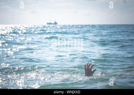 Unica mano di annegamento di uomo in mare per chiedere aiuto. sticking fuori dall'acqua Foto Stock