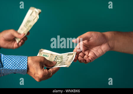 Le mani del commerciante indiano di dare i soldi per il suo partner. Concetti per dare denaro, la corruzione attiva e passiva. Foto Stock