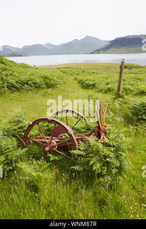 Vintage attrezzature agricole abbandonate su un rilievo beach sull'Isola di Ulva guardando al Isle of Mull, Ebridi Interne, Scotland, Regno Unito Foto Stock
