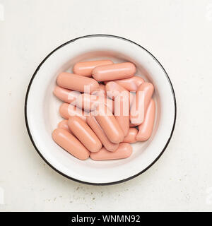 Salumi crudi nella vecchia ciotola di metallo incrinato su sfondo bianco. Vista superiore Foto Stock