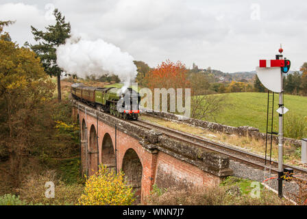 Il treno a vapore 'Tornado' restaurato con carrozze che attraversano un ponte verso un segnale con pennacchio di fumo Foto Stock