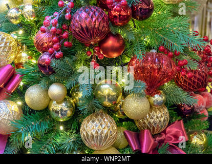 Albero di Natale decorato con giocattoli colorati fiocchi e bacche. Sfondo di natale. Foto Stock