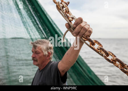 Pescatore commerciale azienda catena arrugginito, il fuoco selettivo sulla mano a spiovente. Foto Stock