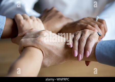 Close up di diverse persone si uniscono le mani che mostra l'unità Foto Stock