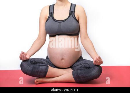 Giovane donna incinta a praticare yoga in lotus pongono. Futura madre meditare Foto Stock