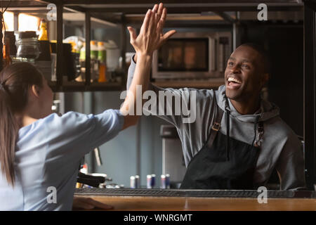 Emozionato African American barista dando alta cinque con la donna sul lavoro Foto Stock