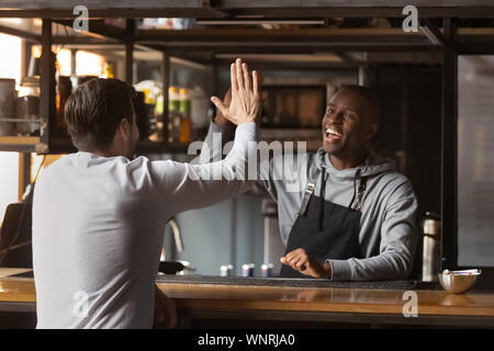 Sorridente African American barista dando alta cinque con il cliente Foto Stock
