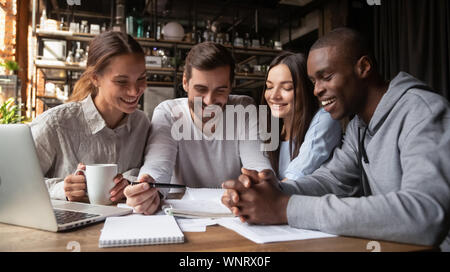 Diversi amici analizzando i documenti insieme, facendo i compiti in cafe Foto Stock