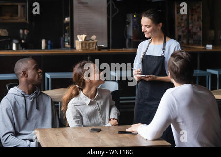 Diversi amici facendo ordine in cafe, sorridente cameriera che serve i clienti Foto Stock