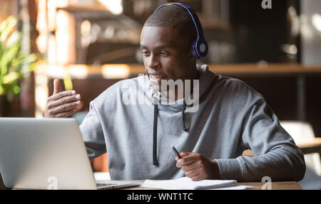 African American uomo nelle cuffie rendendo la chiamata video in cafe Foto Stock