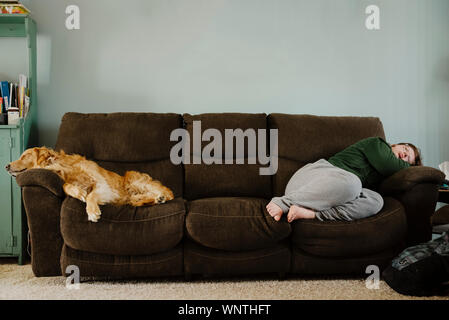 Golden Retriever e teen girl recante sul lettino in ambienti chiusi. Foto Stock