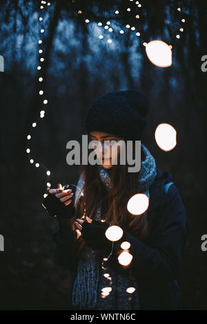 Giovane donna parigamba tenendo le luci di Natale rimanendo in posizione di parcheggio Foto Stock