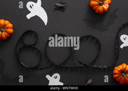 Decorazioni di Halloween, zucche, fantasmi, testo segno "BOO' su sfondo nero. Concetto di Halloween. Appartamento laico, vista dall'alto, overhead. Foto Stock
