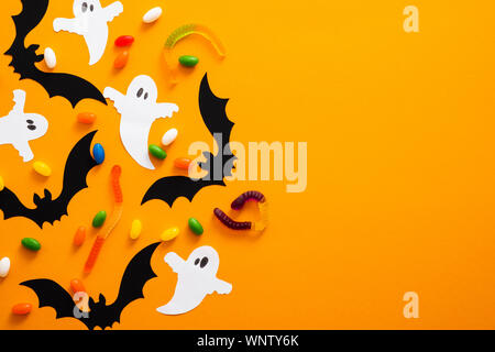 Happy halloween Concetto di vacanza. Decorazioni di Halloween, pipistrelli, fantasmi, candy su sfondo arancione. Festa di Halloween biglietto di auguri mockup con spazio di copia Foto Stock