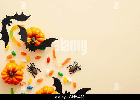 Moderna sullo sfondo di Halloween con zucche, candy, pipistrelli, decorazioni con copia spazio per il testo. Isolato su pastello sfondo beige. Appartamento laico, vista dall'alto, Foto Stock