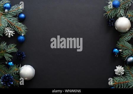 Telaio di natale di confine con il blu e il nastro delle decorazioni moderne, baubles, Abete rami scuri su sfondo nero. Elegante banner di Natale mockup, Foto Stock