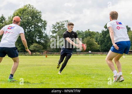 Amatori rugby touch player (maschio, 20-30 y) si prepara a passare la palla al compagno di squadra, come due avversari la faccia di lui a fare il paranco Foto Stock