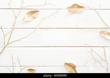 Composizione d'autunno. Cornice fatta di foglie di autunno e decorazioni dorate di legno su sfondo bianco. Appartamento laico, vista dall'alto, overhead. Nordic, hygge, intimo hom Foto Stock