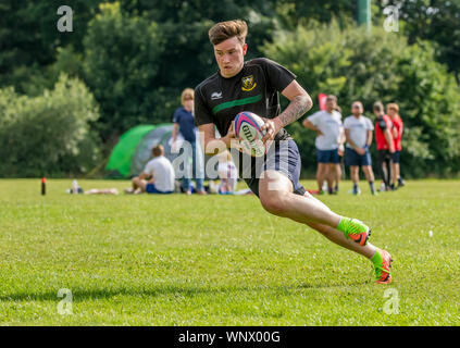 Amatori rugby touch player (maschio, 20 y) passi laterali con palla da rugby in mani Foto Stock