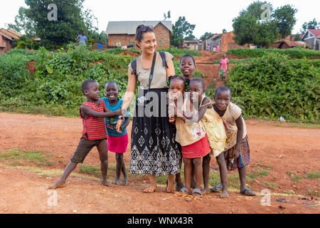 Un bianco-pelato volontario (denominata 'mzungu' o 'muzungu' dalla gente del luogo) tenendo le mani con bambini ugandesi in una zona rurale. Foto Stock