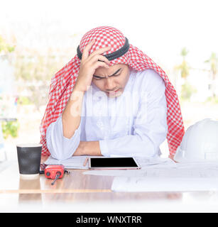 Seriamente Arabian imprenditore lavora in avvio moderno ufficio con computer tablet e il documento sul tavolo. Foto Stock