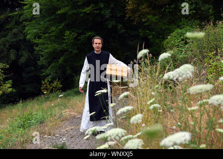 04 settembre 2019, della Renania settentrionale-Vestfalia, Bochum: Padre Justinus passeggiate attraverso il giardino di erbe aromatiche del monastero cistercense nel distretto di Stiepel. Nella sua produzione egli produce una elevata percentuale di gin e lo chiama "onatic dry gin'. Le erbe aromatiche di cui ha bisogno sono piantate e coltivate nel giardino del monastero. Egli riceve il ginepro provenienti dalla Toscana e il grano da cui l'alcool è ottenuto egli riceve dalla madre Abbazia di Heiligenkreuz nella Foresta Viennese. Nel monastero stesso egli non è permesso di bruciare qualsiasi gin perché non hanno alcun diritto di distillazione. Per questo egli unità ad un produttore Foto Stock