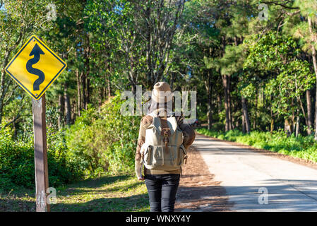 Viaggiatore Da Solo la donna che sta portando uno zaino è in piedi per la selvaggia di mattina in vacanza perché ama viaggiare nella foresta. Foto Stock
