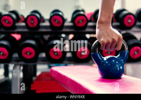 Attrezzature sportive in palestra concetto .kettlebells blu sulla sedia rossa nella moderna palestra sport e fitness.allenamento lifestyle . Foto Stock