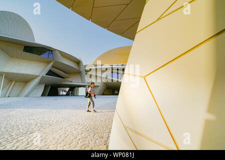 DOHA IN QATAR - 10 luglio 2019; Tourist attraversa il cortile del Museo Nazionale del Qatar insolito ma impressionante design forma è ispirata a rosa del deserto o cristallo Foto Stock