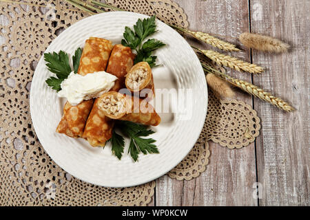 Piastra con frittelle con carne e la tazza di tè su un vecchio sfondo di legno Foto Stock