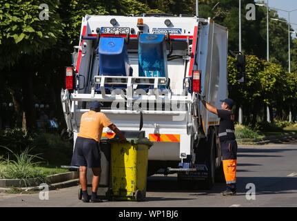 Bucarest, Romania - 29 agosto 2019: due lavoratori servizi igienici svuotare il cestino lattine in un garbage auto, a Bucarest Foto Stock