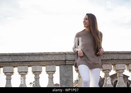 Donna sorridente mentre appoggiata sulla ringhiera di pietra a Boadilla del Monte Foto Stock