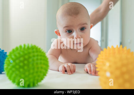 Funny little baby giocando con palline di gomma. Il bambino impara il mondo Foto Stock