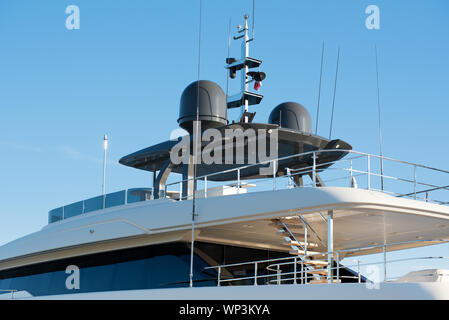 Il radar e apparecchiature di navigazione sul tetto di un bianco di lusso yacht a motore contro il cielo blu Foto Stock