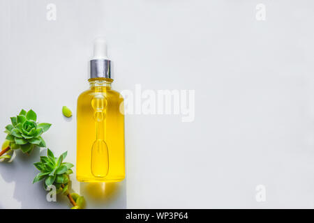 Siero con vitamina C naturale, olio cosmetico in una bottiglia di vetro con una pipetta. Sfondo Llight Foto Stock