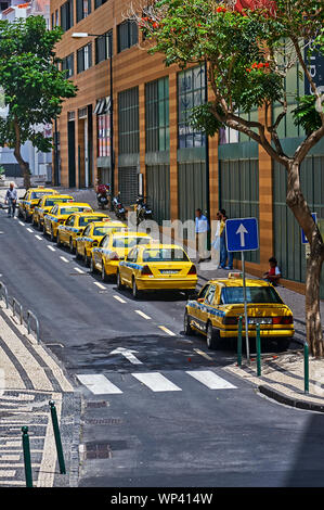 Funchal, la capitale dell'isola di Madera, e linea di iconico giallo taxi su una strada nel centro della città Foto Stock